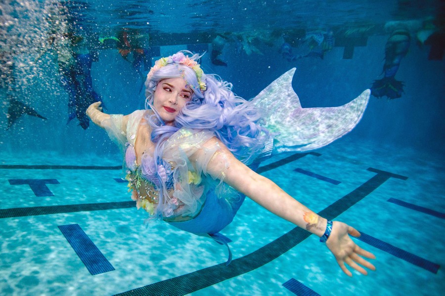 A person dressed as a mermaid swims underwater in a pool.