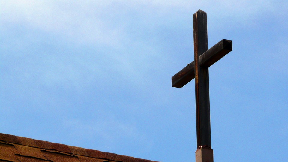 A wooden cross on a rooftop, against a blue sky