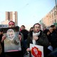 A man holds a photograph of Qassem Soleimani during the general's funeral procession while walking next to others.