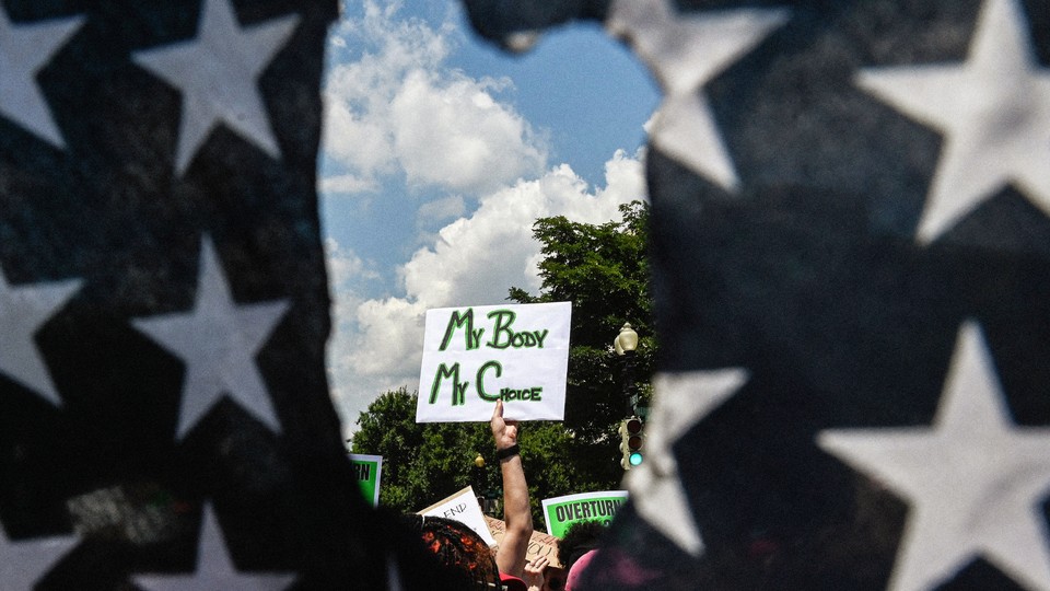 An abortion demonstration captured through a hole in an American flag