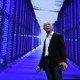 Jeff Bezos stands in front of a purple, blue, and black data center.