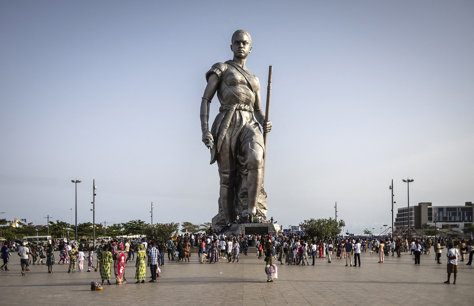 People gather around the base of a tall statue of an Amazon warrior.