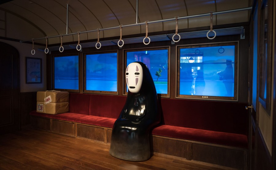 A statue of a character from a Miyazaki film sits inside a set resembling a passenger train car.