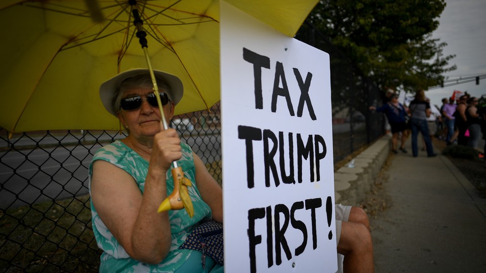 A woman holds a sign during demonstrations as U.S. President Donald Trump delivers a speech on tax reform.