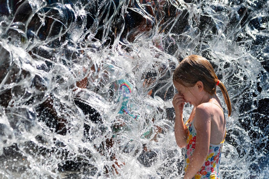 A young girl holds her nose before plunging through a curtain of falling water.