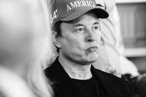 Black-and-white photo of Elon Musk in a campaign cap