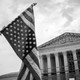 Person waving upside-down flag in front of Supreme Court building