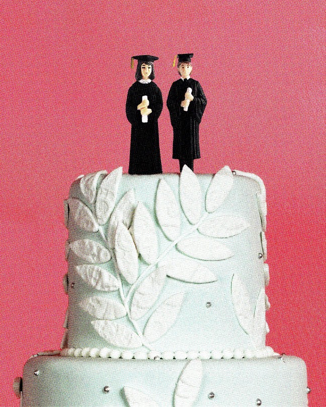 A wedding-cake topper with two people in graduation gowns