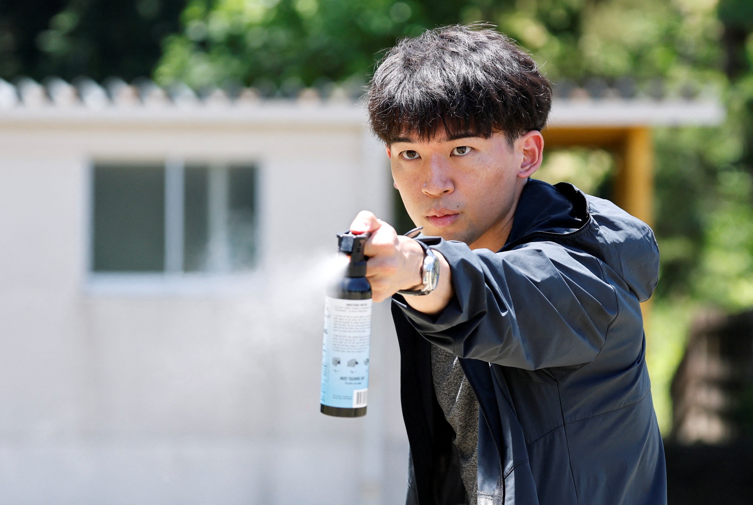A person sprays a canister of bear spray.