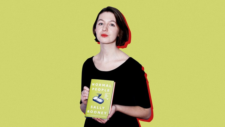 Sally Rooney poses with a copy of her book "Normal People" against a yellow background.