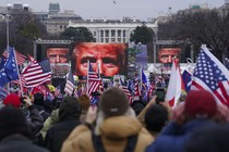 A crowd of Trump supporters gather in front of the White House, before several large video screens displaying the face of President Trump.