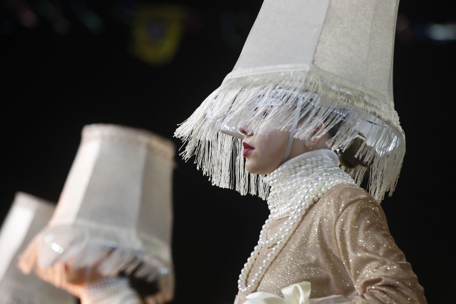 Several performers wear costumes including headgear shaped like lampshades.