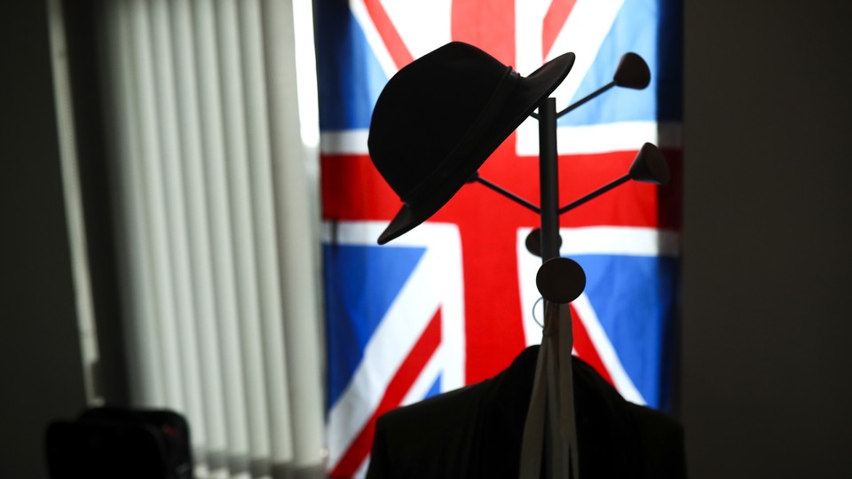 An image of a hat hanging on a hook in front of the Union Jack flag.