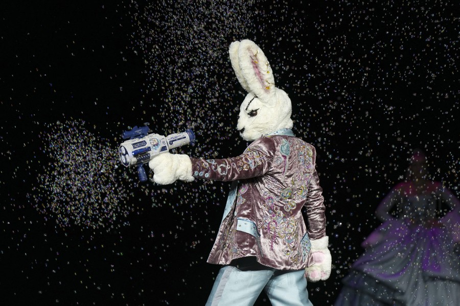 A model wearing a bunny costume points and pulls the trigger of a plastic gun that fires bubbles.