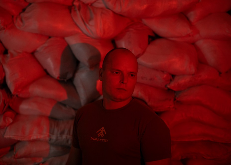 A man standing in front of sand bags in red lighting.