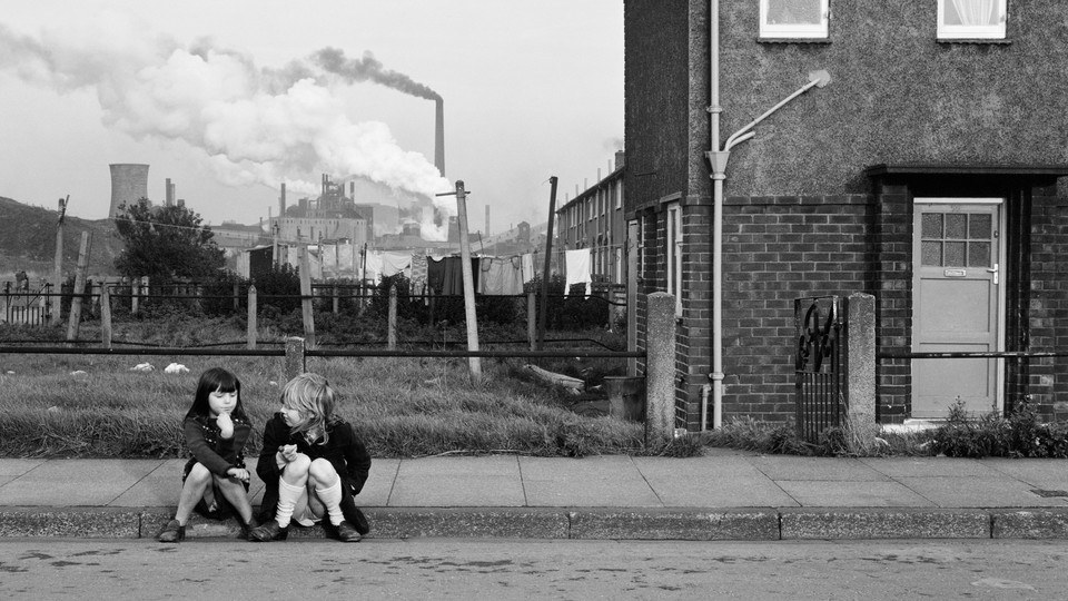 Two children sitting on the sidewalk alone