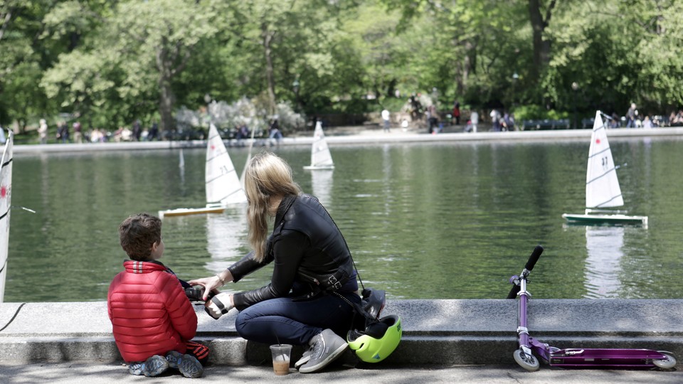 A mother and child look at miniature sailboats. 