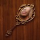 a fancy mirror on a wooden surface, the face of a black woman is reflected in the mirror