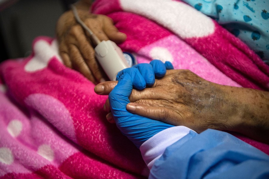 A health professional holds the hand of a COVID-19 patient.