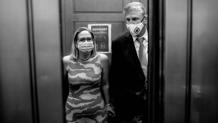A black-and-white photo of Joe Manchin and Kyrsten Sinema in a Capitol Hill elevator