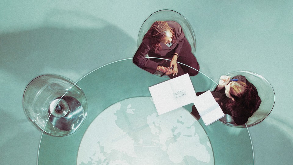 Corporate people sit at a desk, looking at papers together