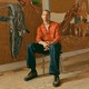 A photo of Chase Hall sitting in front of paintings