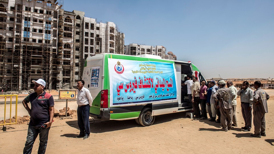 Egyptian workers line up near a van for an examination check-up for Hepatitis C