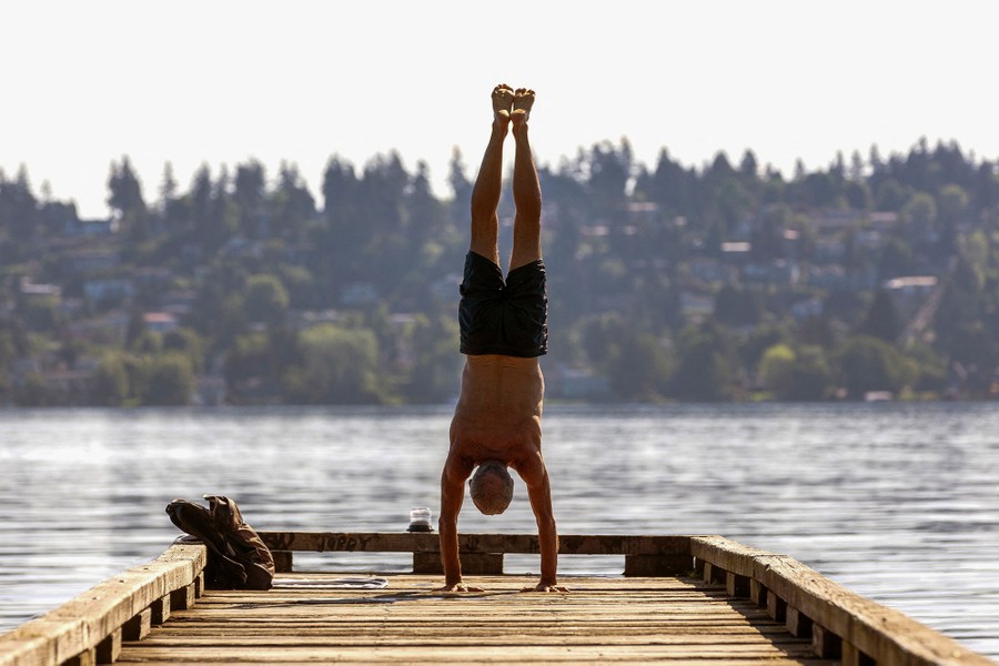 A person does a handstand on a small dock.