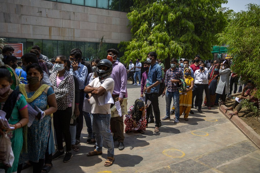 People line up, standing close together, waiting for a COVID-19 test.