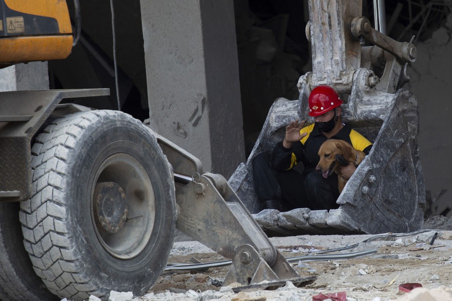 A rescue worker and his search dog prepare to be lifted in the bucket of an excavator.