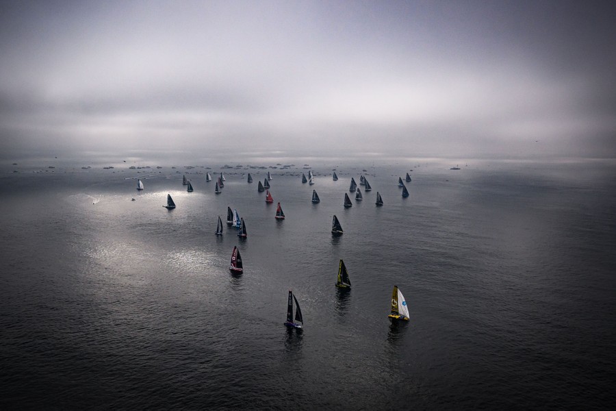 An elevated view of dozens of racing sailboats at the start of a race