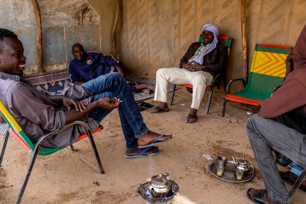 Adou Ama (middle, back), sits under a hangar in downtown Agadez, where he spends his days with other former smugglers drinking tea and smoking cigarettes. / Peter Tinti