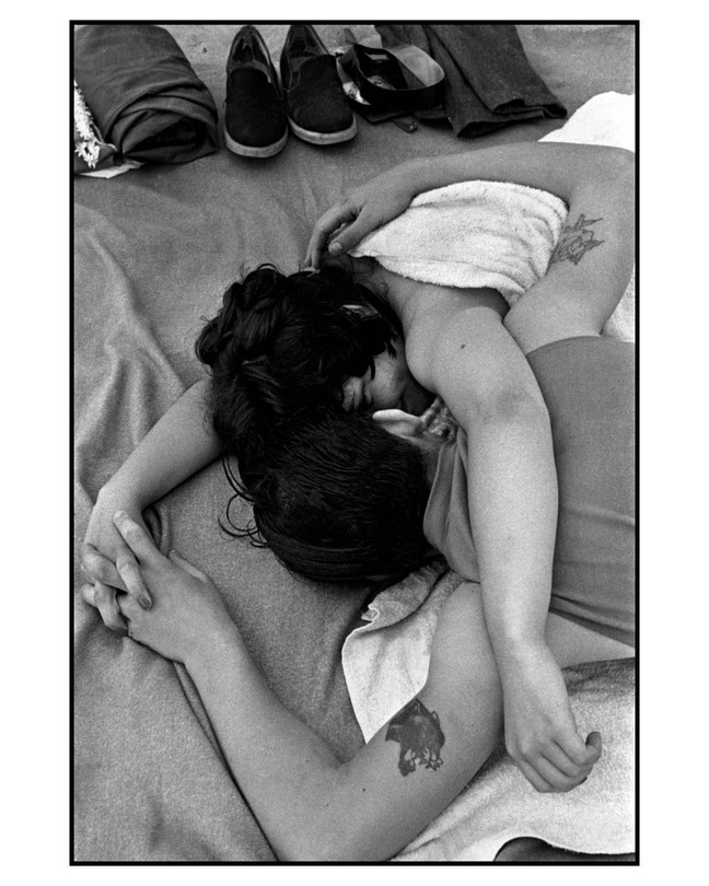 black and white photo of a tattooed couple laying on a beach towel