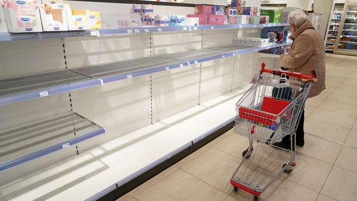 A woman shopping at a store with empty shelves.