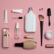 Numerous beauty products without labels arranged on a pink surface