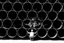 Large pipes for the Baltic Sea pipeline Nord Stream 2 are stacked in a storage area in the ferry port of Sassnitz/Neu Mukran. An employee of the responsible company Wasco crouches in front of the pipes.