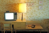 Vintage photo of a living room with a landline, lamp, and CRT television sitting on a table