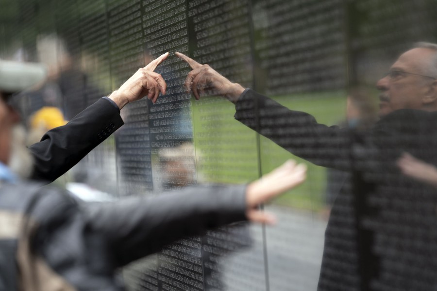 A person points to the names of the fallen soldiers at the Vietnam Veterans Memorial.