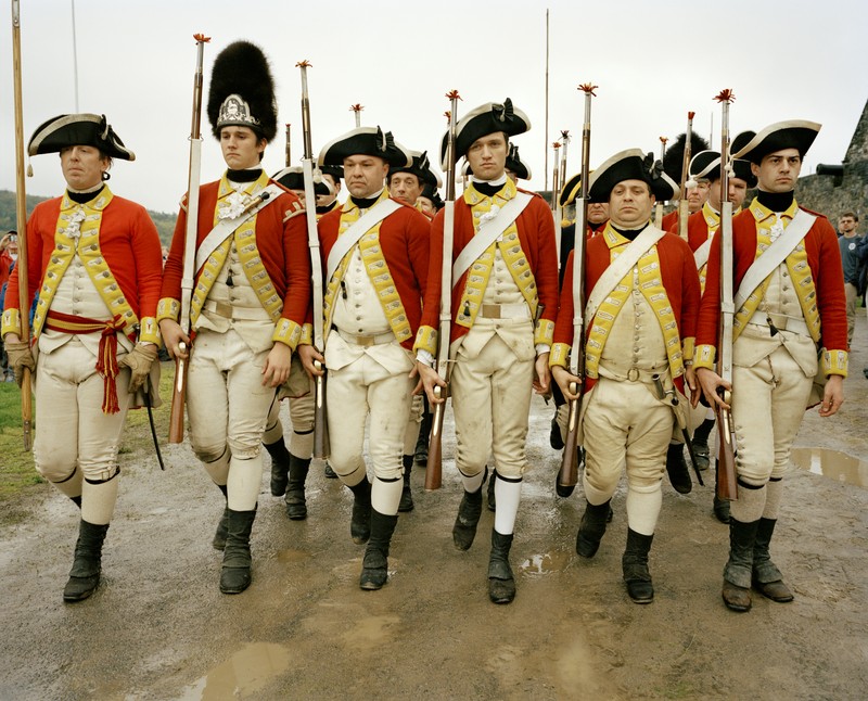 photo of reenactors as a troop of English soldiers marching together in formation to prepare for a musket demonstration