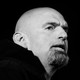 A black-and-white photo of John Fetterman, Pennsylvania candidate for U.S. Senate, against a black backdrop