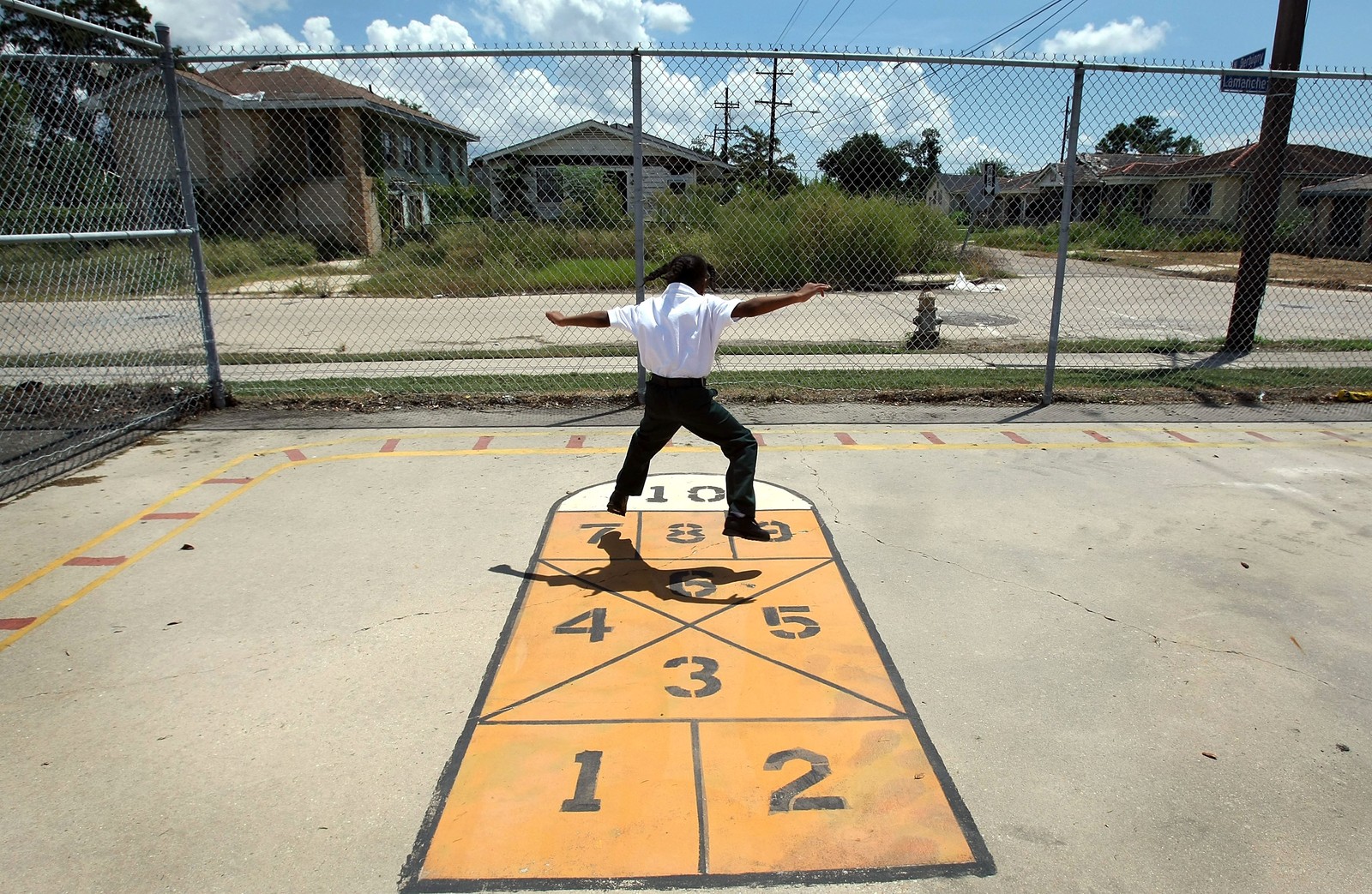 A child plays hopscotch in a schoolyard.
