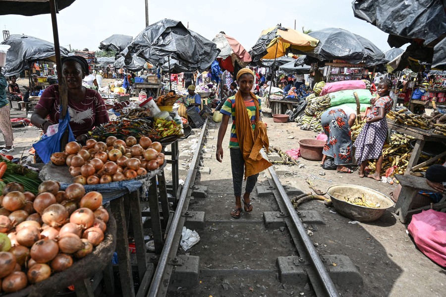 People walk in an open-air market along railroad tracks.