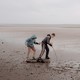 Two kids poke a stick into the mud of a dried reservoir.
