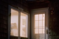 a door and a window to a house revealing a lit interior