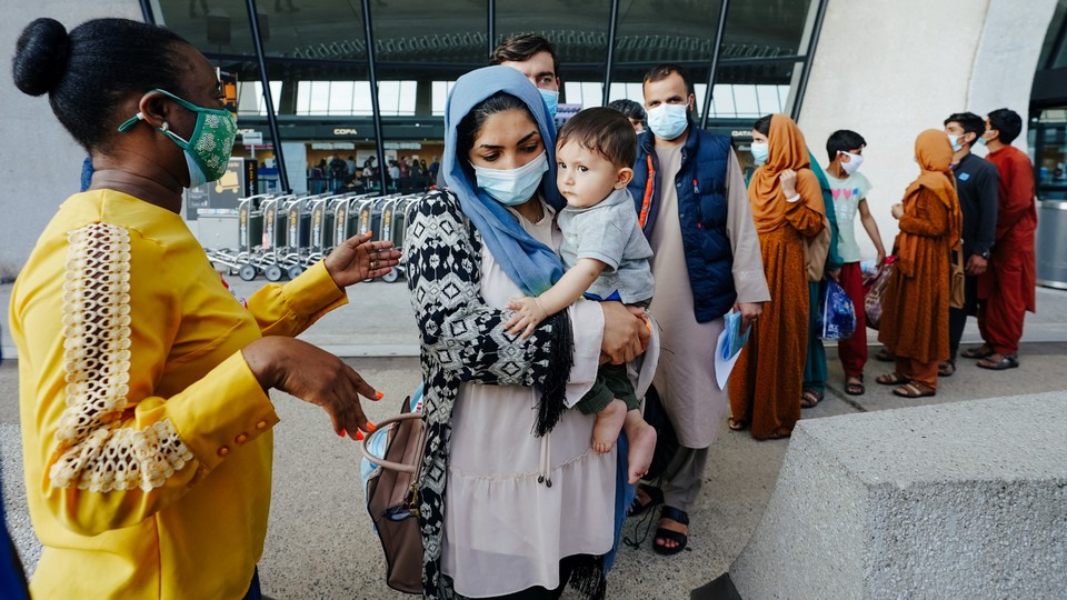 Afghan refugees line up to board a bus upon arrival at Dulles International Airport in Dulles, Virginia.