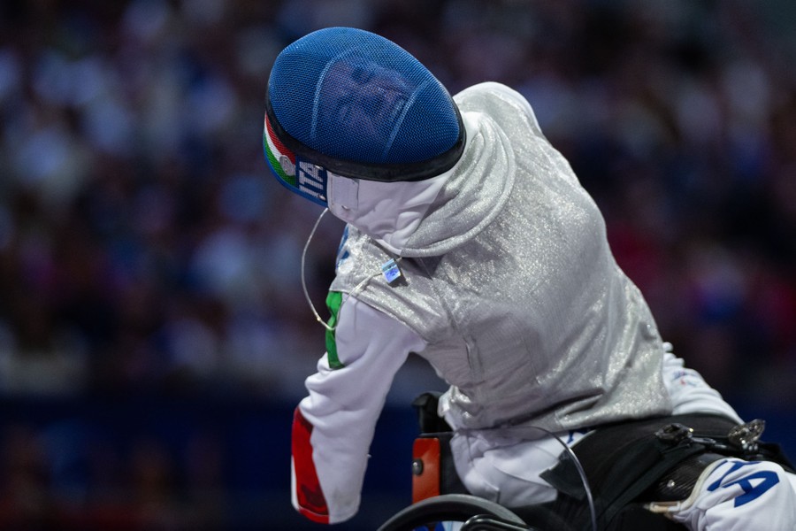 A fencer in a wheelchair shouts and reacts after scoring a point.