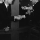 A black and white photo of two men shaking hands in a dark bar