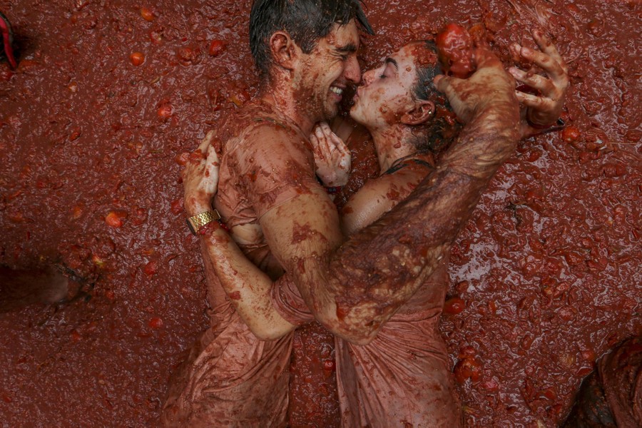 A couple embraces in a mass of squashed tomatoes during a food-fight festival.