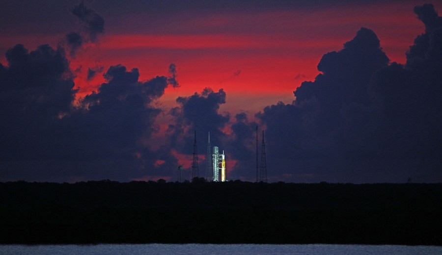 A distant sunrise view of the SLS rocket standing on its launch pad.