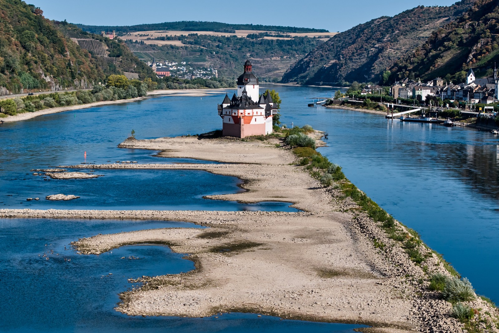 A small historic toll castle sits in the middle of a river, which is at very low level during a drought.